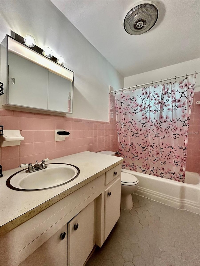 full bathroom featuring shower / bath combination with curtain, vanity, tile walls, tile patterned flooring, and toilet