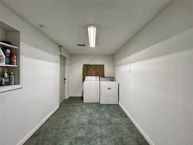 laundry room with a textured ceiling and washing machine and clothes dryer