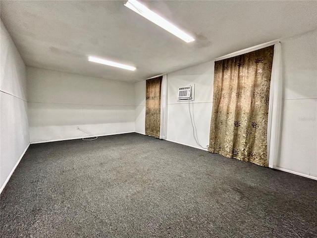 spare room featuring dark carpet and an AC wall unit