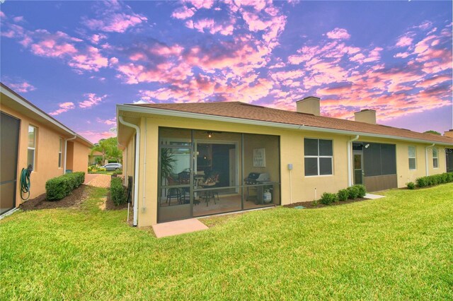 1644 Linz Ct, Winter Haven, FL 33884 - back of house at dusk with a chimney, a sunroom, a yard, and stucco siding