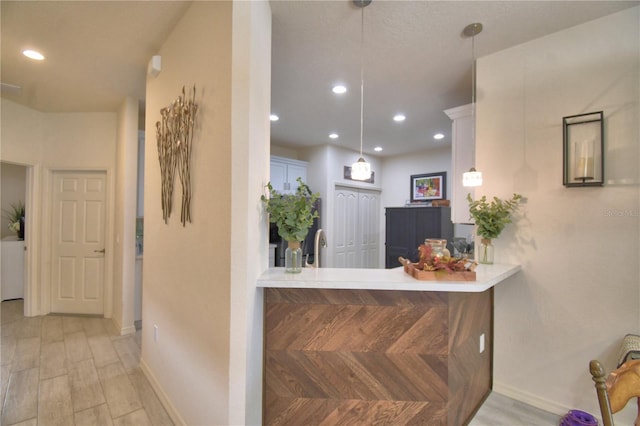 interior space featuring kitchen peninsula, pendant lighting, light hardwood / wood-style floors, and white cabinetry