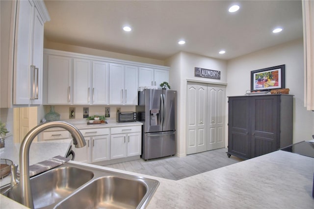 1644 Linz Ct, Winter Haven, FL 33884 - kitchen featuring stainless steel refrigerator with ice dispenser, a sink, white cabinets, light countertops, and light wood-style floors