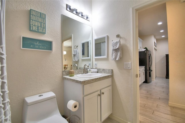 1644 Linz Ct, Winter Haven, FL 33884 - bathroom featuring vanity, wood finished floors, toilet, a textured wall, and baseboards
