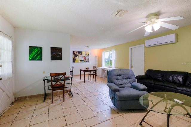 living room with ceiling fan, light tile patterned flooring, an AC wall unit, and a textured ceiling