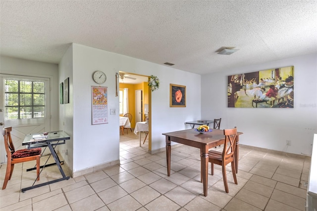 dining area with ceiling fan, light tile patterned floors, and a textured ceiling