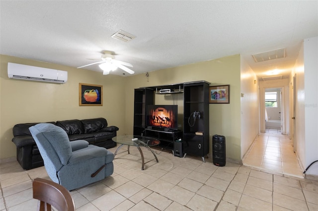 living room featuring a wall mounted AC, ceiling fan, light tile patterned floors, and a textured ceiling