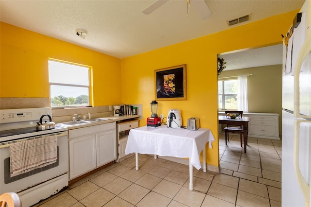 kitchen featuring white appliances, a textured ceiling, sink, light tile patterned floors, and white cabinets