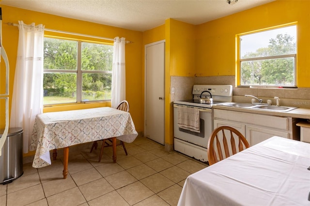 kitchen featuring electric stove, a wealth of natural light, sink, and light tile patterned flooring