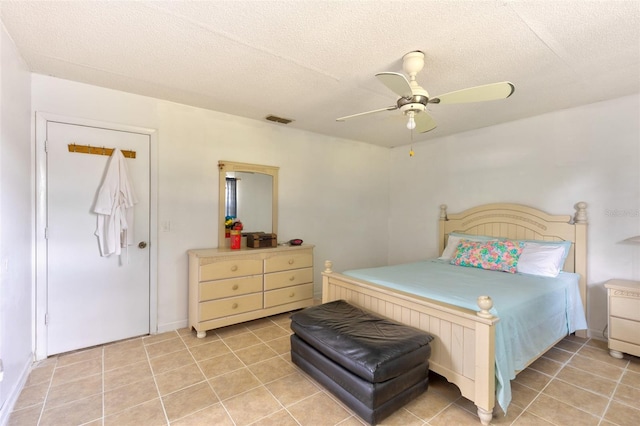 tiled bedroom with ceiling fan and a textured ceiling