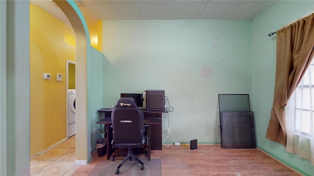 home office with washer / dryer, a textured ceiling, and light wood-type flooring