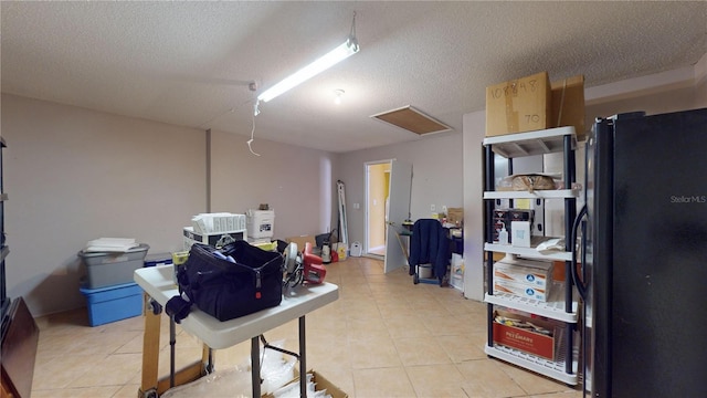 basement featuring a textured ceiling and black fridge