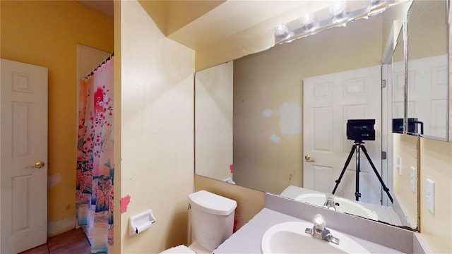 bathroom featuring toilet, vanity, and curtained shower