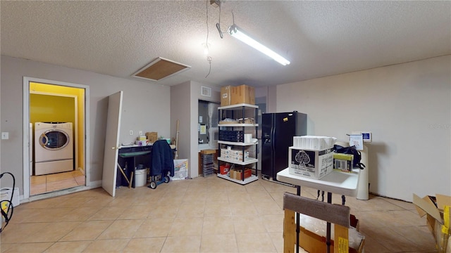 interior space featuring light brown cabinetry, a textured ceiling, washer / dryer, and black fridge