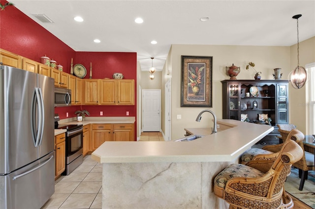 kitchen featuring sink, stainless steel appliances, pendant lighting, a kitchen bar, and light tile patterned flooring