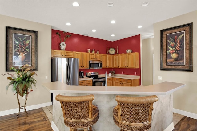 kitchen featuring a large island, a breakfast bar, appliances with stainless steel finishes, and light hardwood / wood-style flooring