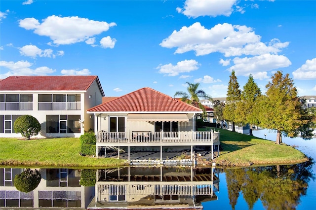 rear view of house with a water view and a yard