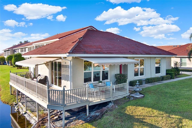 back of property featuring a wooden deck and a lawn