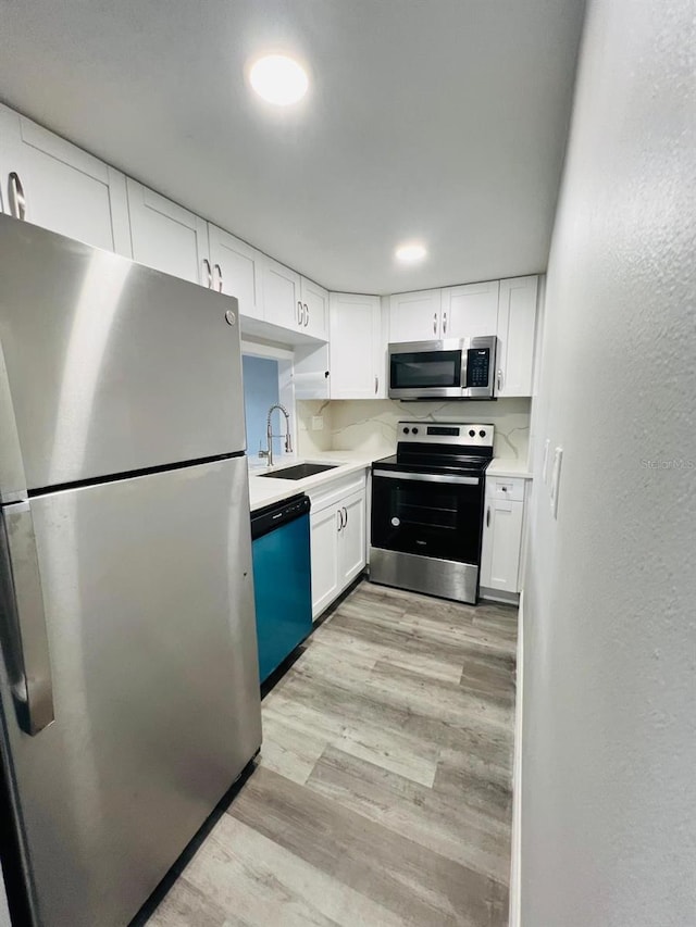 7108 Waterside Dr Unit 103, Tampa, FL 33617 - kitchen with appliances with stainless steel finishes, light wood-style flooring, a sink, white cabinetry, and light countertops