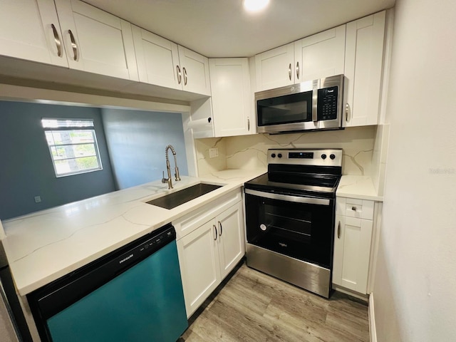 kitchen featuring sink, light hardwood / wood-style flooring, light stone counters, white cabinetry, and stainless steel appliances