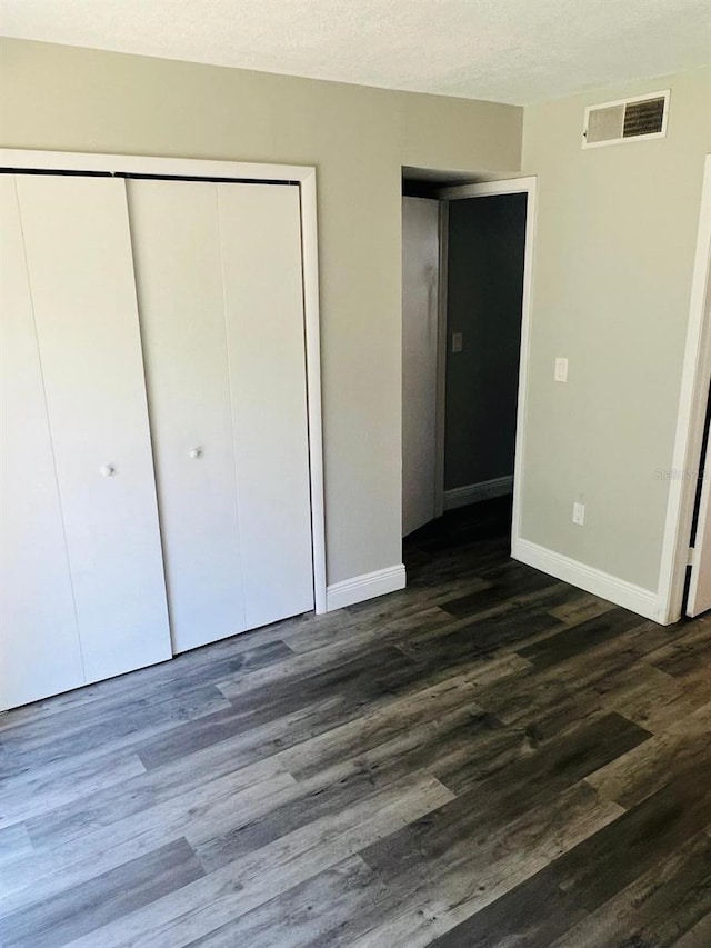 unfurnished bedroom featuring a closet, dark hardwood / wood-style flooring, and a textured ceiling