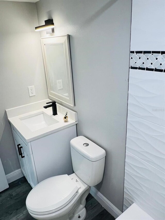 7108 Waterside Dr Unit 103, Tampa, FL 33617 - bathroom featuring vanity, toilet, wood finished floors, and baseboards