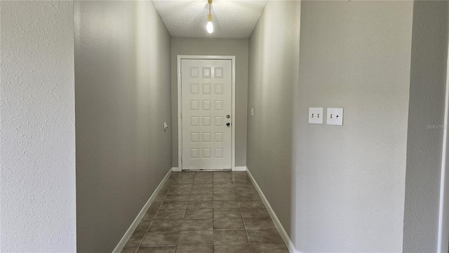 doorway to outside featuring dark tile patterned flooring and a textured ceiling