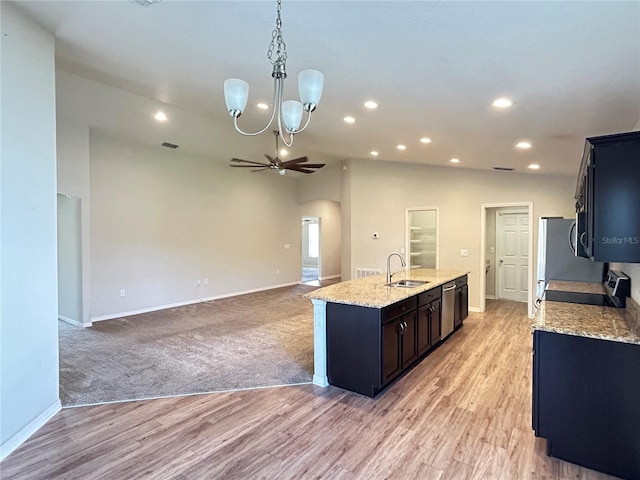 kitchen featuring a center island with sink, stove, dishwasher, decorative light fixtures, and sink