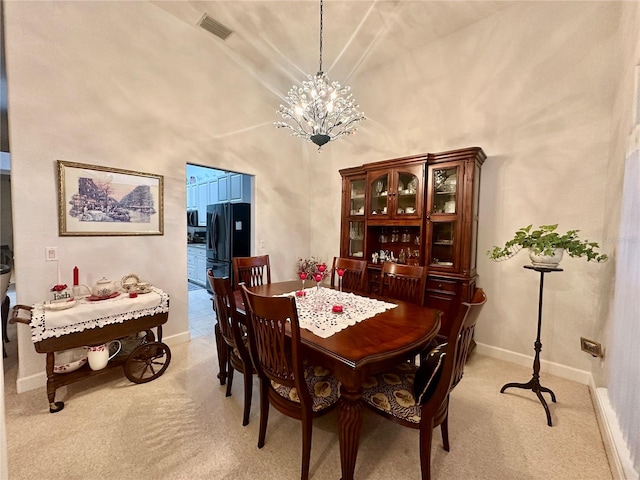 carpeted dining area with a high ceiling and a chandelier