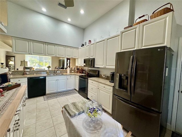 kitchen featuring sink, black appliances, white cabinets, a high ceiling, and butcher block counters