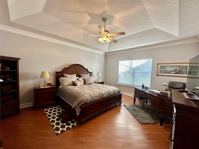 bedroom featuring hardwood / wood-style floors, ceiling fan, crown molding, and a tray ceiling