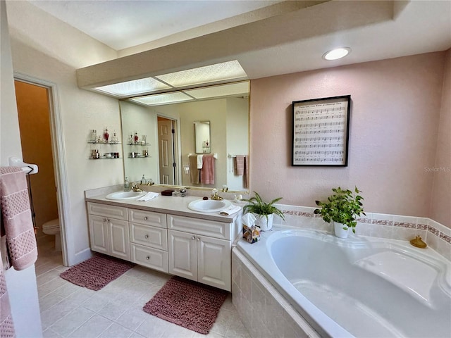 bathroom with tile patterned flooring, vanity, a relaxing tiled tub, and toilet