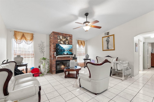 living room with ceiling fan, light tile patterned floors, a fireplace, and vaulted ceiling