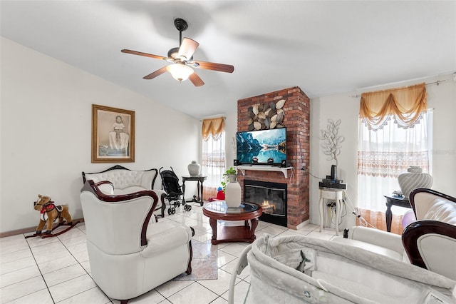 tiled living room featuring ceiling fan, a fireplace, a wealth of natural light, and vaulted ceiling