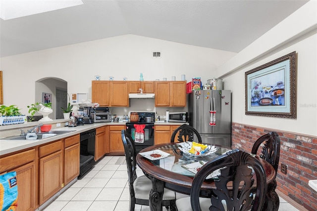 kitchen with brick wall, sink, black appliances, light tile patterned floors, and lofted ceiling