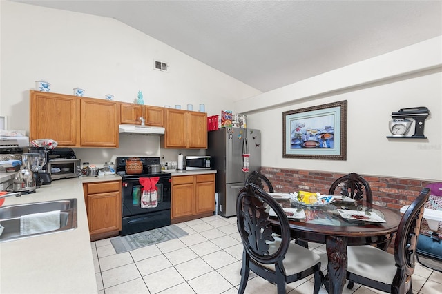 kitchen featuring lofted ceiling, sink, light tile patterned floors, stainless steel appliances, and brick wall