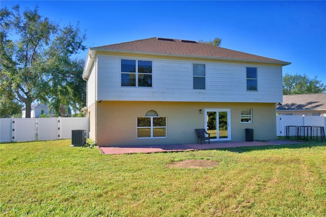 rear view of property with cooling unit, a yard, and a patio