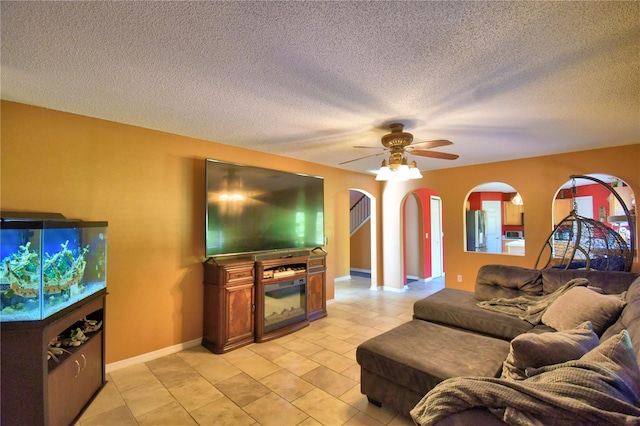 living room featuring ceiling fan and a textured ceiling