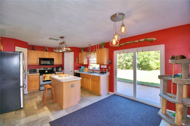 kitchen with a kitchen breakfast bar, a center island, stainless steel appliances, and hanging light fixtures