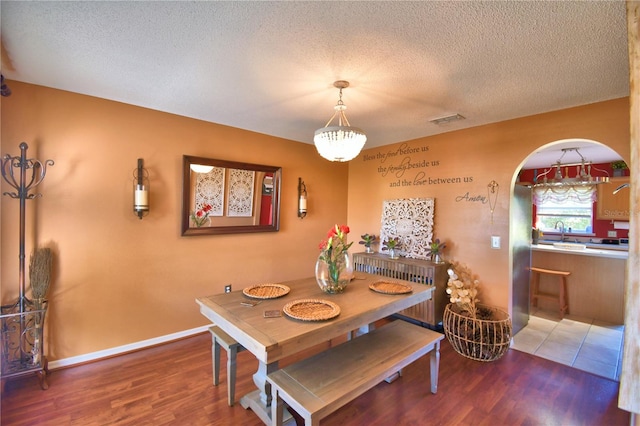 dining area featuring sink, dark hardwood / wood-style flooring, and a textured ceiling