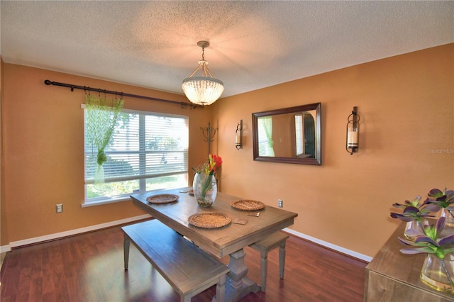 dining space with a textured ceiling, dark hardwood / wood-style floors, and a notable chandelier