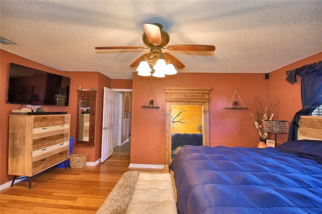 bedroom with hardwood / wood-style floors, a textured ceiling, and ceiling fan