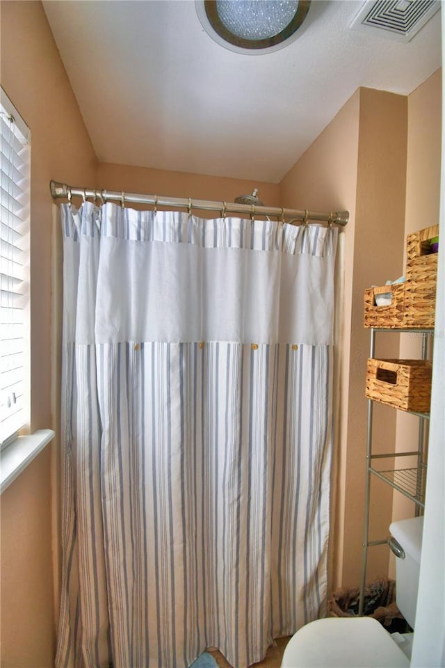 bathroom featuring a shower with shower curtain and toilet