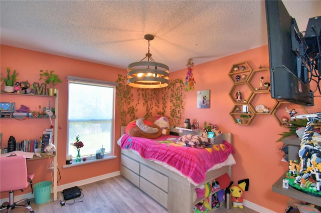 bedroom featuring light hardwood / wood-style floors, a textured ceiling, and an inviting chandelier