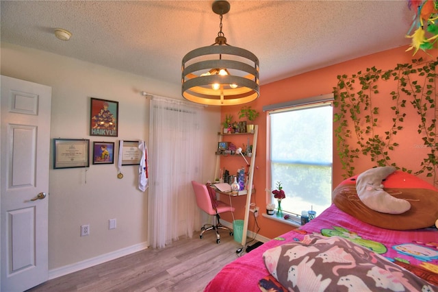 bedroom featuring wood-type flooring, a textured ceiling, and a notable chandelier