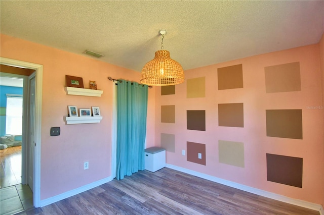 unfurnished room with hardwood / wood-style floors and a textured ceiling