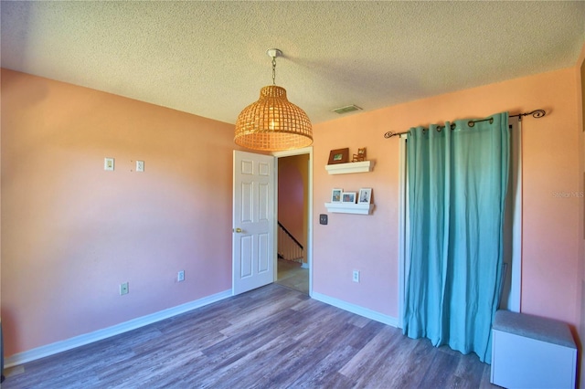 unfurnished room with a textured ceiling and dark hardwood / wood-style flooring