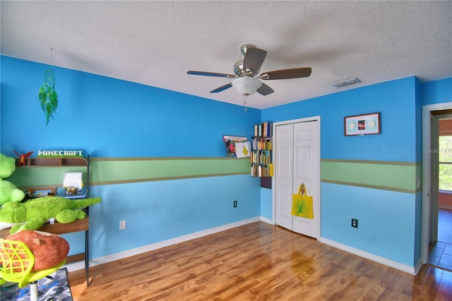 unfurnished bedroom featuring hardwood / wood-style floors, ceiling fan, a textured ceiling, and a closet