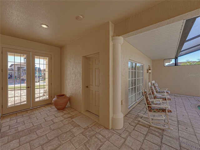 doorway with french doors, a textured ceiling, and vaulted ceiling