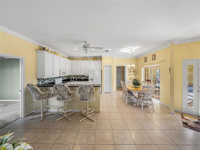 kitchen featuring kitchen peninsula, white cabinets, light tile patterned floors, and ornamental molding