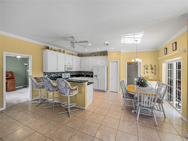 kitchen featuring white cabinetry, kitchen peninsula, crown molding, white appliances, and light tile patterned flooring